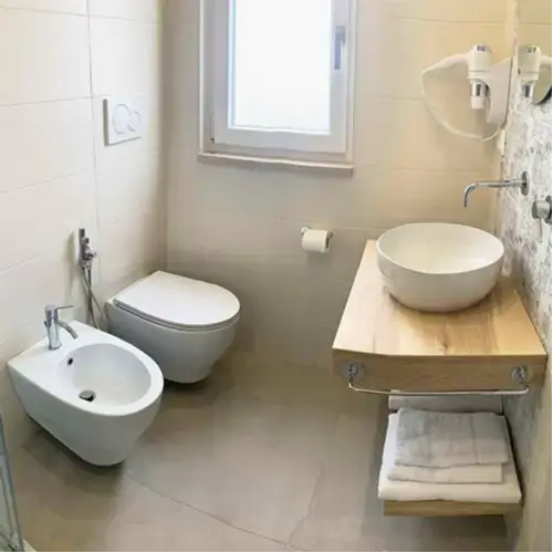 Bagno moderno dal design essenziale con dettagli in legno chiaro presso Tenuta Verdolivo a Ostuni.