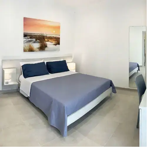 Camera matrimoniale luminosa dal design minimalista con dettagli blu e quadro decorativo presso Tenuta Verdolivo